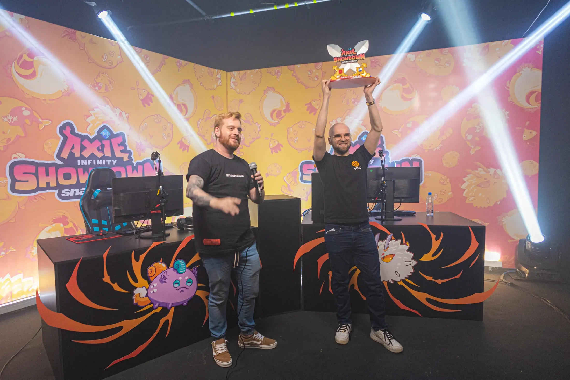 Final presencial do Axie Infinity Showdown, com palco produzido, apresentador e campeão erguendo o troféu