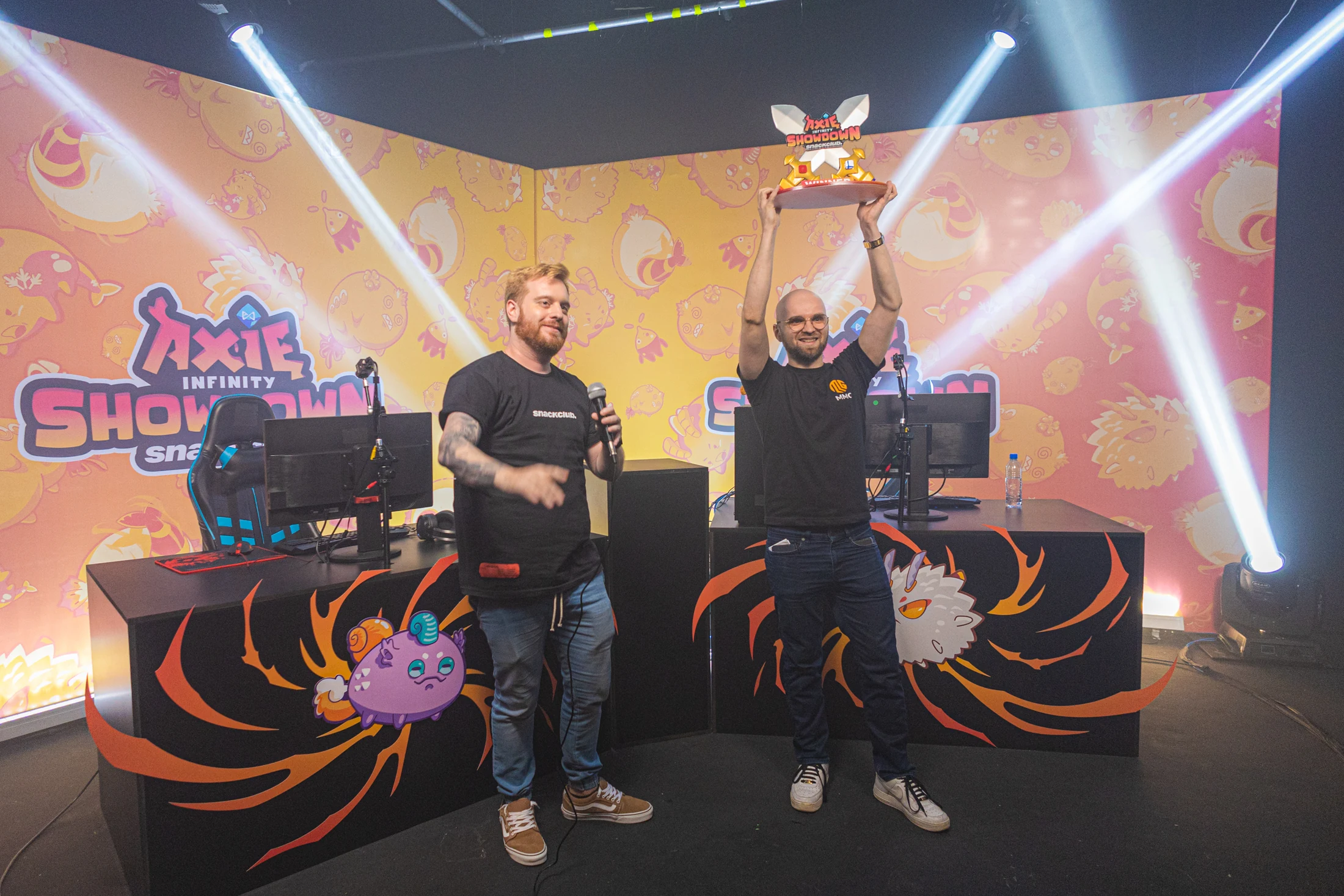Final presencial do Axie Infinity Showdown, com palco produzido, apresentador e campeão erguendo o troféu